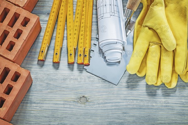 Red bricks leather protective gloves wooden meter construction drawings bricklaying trowel building concept