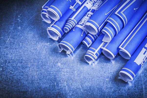 Blue rolled blueprints on metallic background construction concept