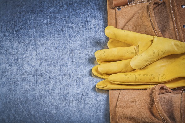 Pair of protective gloves toolbelt on metallic background construction concept