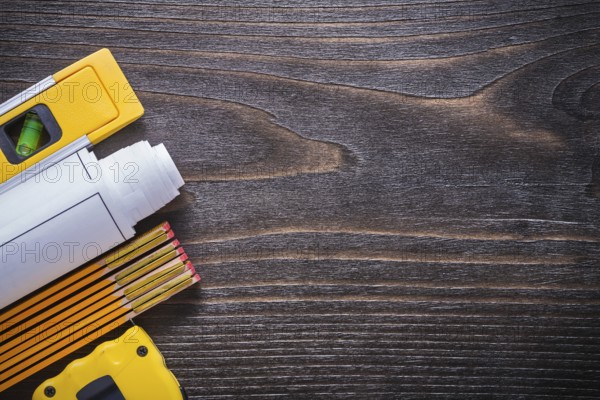 Blueprints construction level measuring tape and wooden meter on vintage wood board copy space image maintenance concept