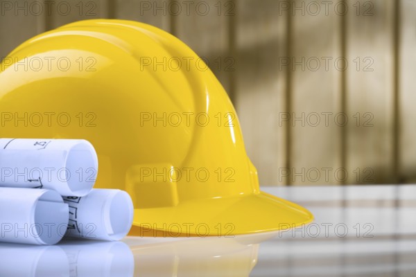 Blueprints and yellow helmet on white table