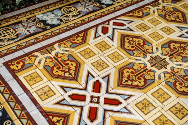 Floor tiles with arabesque ornaments in yellow, white and red colors.
