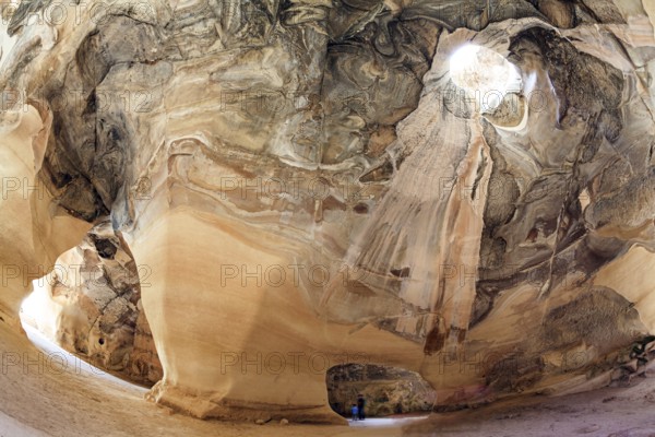 The famous underground national park Beit Guvrin, Israel. Bell Caves - quarries of the 7th century AD. Ancient caves for the extraction of building materials. A sunbeam in the ceiling picturesquely illuminates the vaults of the cave. Sunny warm day for a successful excursion