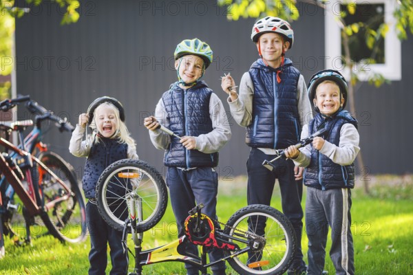 Children mechanics, bicycle repair. Happy kids fixing bike together outdoors in sunny day. Bicycle repair concept. Teamwork family posing with tools for repairing a bicycle in hands outside