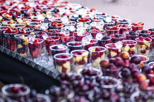 Rows of colorful fruit cups filled with fresh berries displayed on a market stall in the seaside town most commonly referred to as Brighton Beach, in the city of Bright and Hove, East Sussex, England, United Kingdom