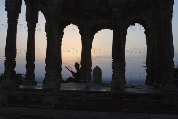 Folksinger playing ravanhatta at sunrise in cenotaph, Rajasthan, India