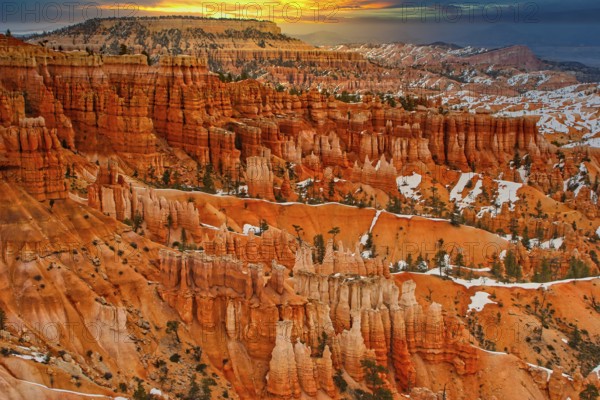 Wide view of a canyon with orange-coloured rocks and snow-covered slopes at sunrise, Bryce Canyon, Utah, America