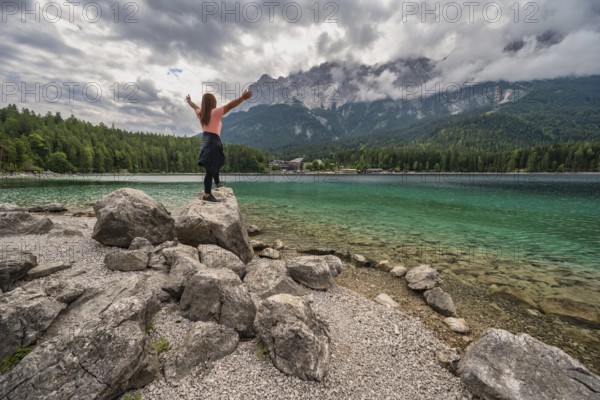 Zugspitze Peak top of Germany Alps mountain range and Eibsee Lake with woman tourist, Garmisch Partenkirchen Germany