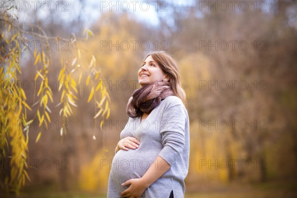 Happy young smiling pregnant woman in autumn park