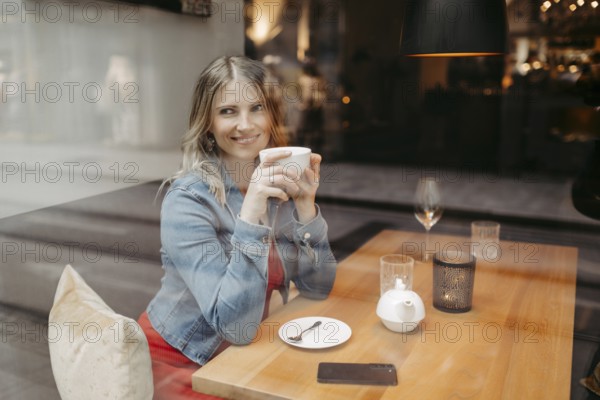 Blonde, attractive woman, 40+, sitting in a coffee house by the window