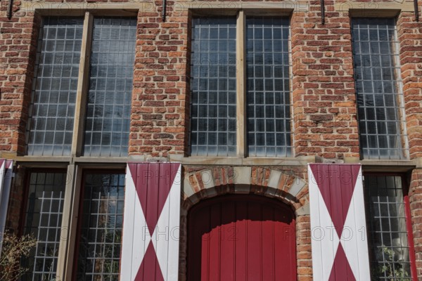 Red brick building with large mullioned windows and red and white shutters, Xanten, Lower Rhine, North Rhine-Westphalia, Germany