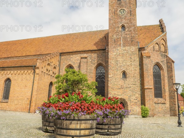 Church in the background with large flower pots in the foreground, historic brick walls, ystad, sweden, baltic sea, scandinavia