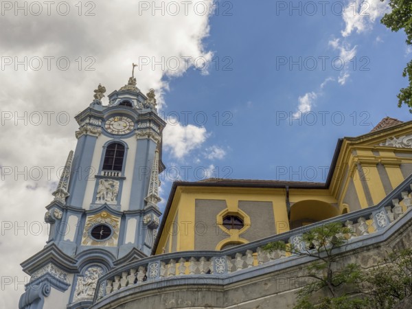 An impressive baroque church tower and a building that both break through the blue sky, Dürnstein, Wachau, Danube, Austria