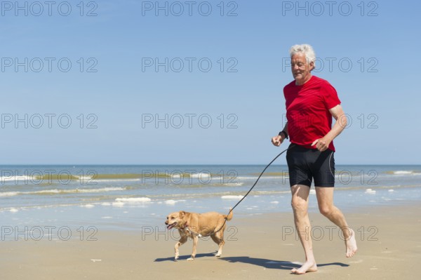 Senior runner with dog at the beach