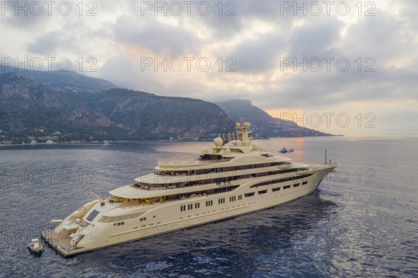 Aerial view of 156-metre superyacht DILBAR, delivered in 2016 by the Lürssen Yachts shipyard to Russian oligarch Alisher Usmanov Alisher Usmanov, General Director of Gazprominvestholding, co-owner of Metalloinwest, owner of publishing house Kommersant. Largest yacht in the world by volume. Currently under arrest at the shipyard due to sanctions against Russia, here at anchor at sunrise on the Cote d'Azur, Alpes-Maritimes, Provence-Alpes-Cote d'Azur, Southern France, France, Mediterranean Sea