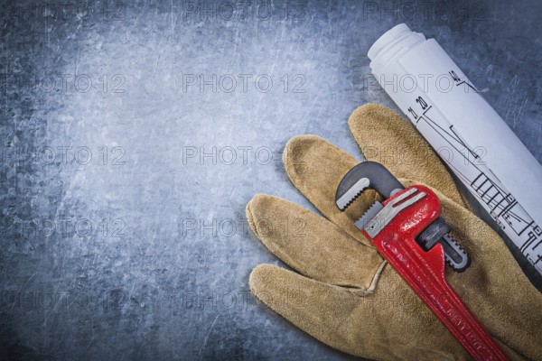 Monkey wrench protective gloves blueprints on scratched metallic background plumbing concept