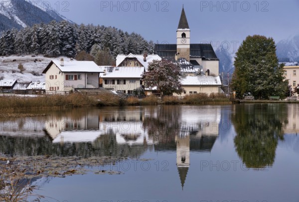 The church in the village Tarasp reflecting in the Taraspsee in the Swiss community Scuol in the canton of Graubunden