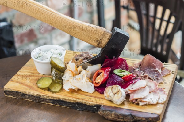 Slices fresh pork meat, lard on wooden board with vegetables, spices, stuck ax on the table