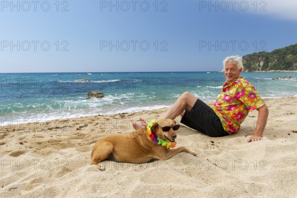Relaxing elderly man with dog laying at the beach