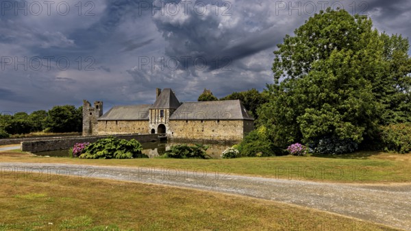 Castle with water and gardens in a tranquil landscape under a dramatic sky, Gratot Castle in Normandy, France