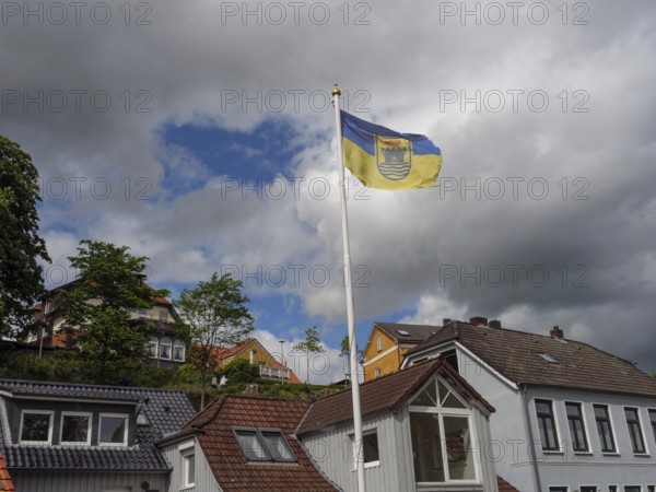 Flag flies over a residential neighbourhood with modern and traditional houses under a cloudy sky, Eckernförde, Schlewsiwg-holstein, Germany
