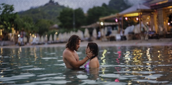 A couple in an intimate moment in the water near the beach during the evening