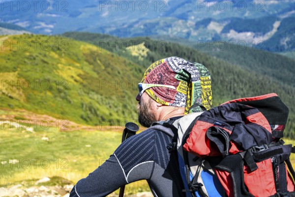 Man hiker on the trail hiking the mountain. A man sitting on a trail and looks at the beautiful Carpathian Mountains. Man enjoying mountain view