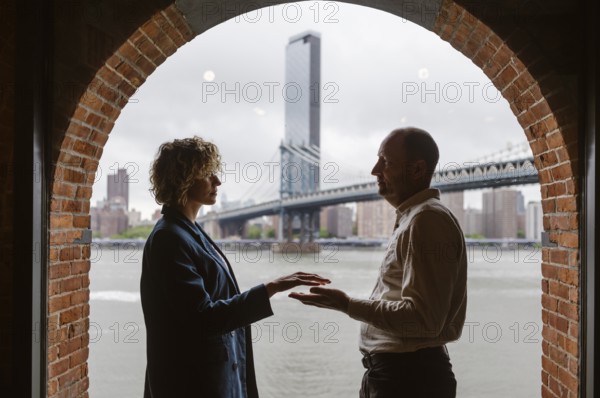 People by the window with Manhattan Bridge in the background, Brooklyn District in New York City - US
