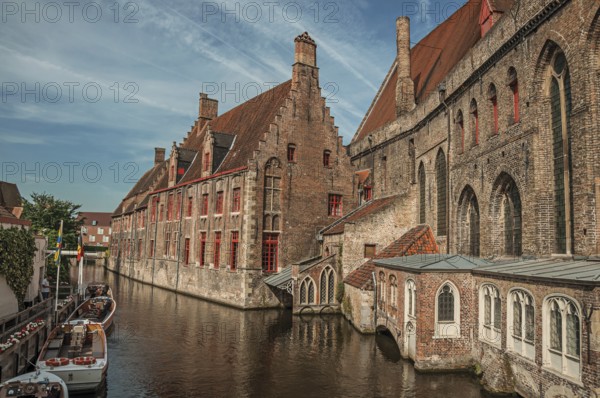 Old buildings on the canal bank, boats and sunny blue sky in Bruges. With many canals and old buildings, this graceful town is a World Heritage Site of Unesco. Northwestern Belgium