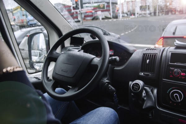 Inside a vehicle with a view of traffic and buildings through the windshield