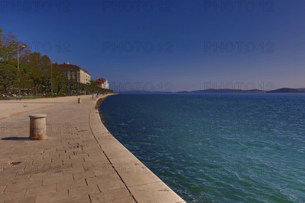 Long promenade along the blue water, with historic buildings and a clear sky in the background, Zadar Dalmatia Croatia