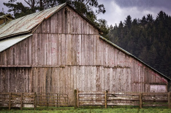 An old barn on a rural farm with trees, sky and clouds