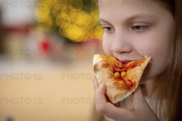 A joyful young child savoring a deliciously tasty slice of pizza, filled with pure happiness in a cozy, warm setting