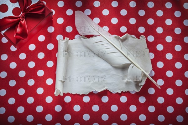 Present box vintage paper roll feather on polka-dot red tablecloth celebrations concept