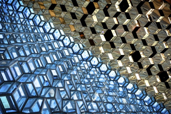 Compact geometric patterns in a glass architecture reflecting blue and gold tones, Harpa Concert Hall, Reykjavik, Iceland
