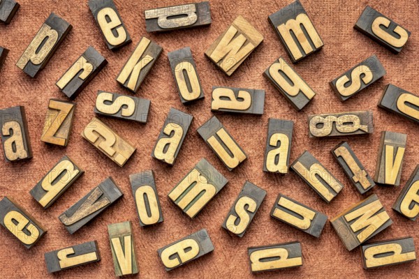 Random letters overhead background - vintage letterpress wood type (inverted image) against brown handmade bark paper