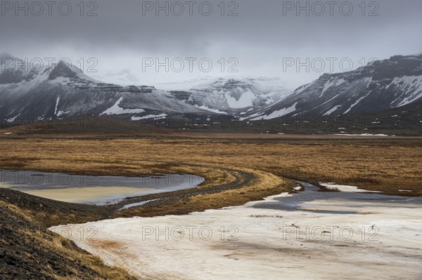 Icelandic dramatic landscape with frozen lake and mountains covered in snow in winter Iceland