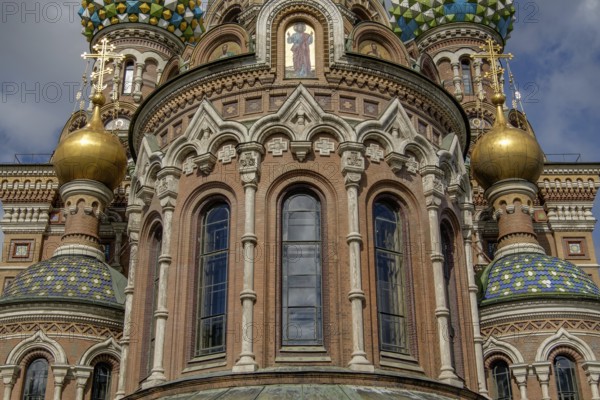 Close-up of a church with beautiful windows, golden domes and colourful mosaics under a cloudy sky, st. petersburg, russia