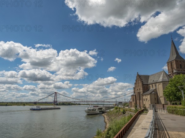 Historic church with a bridge and a ship on the river under a cloudy sky, emmerich, lower rhine, germany