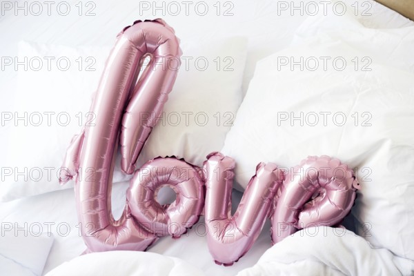 Large pink inflated letters LOVE on linens on the bed. The trend for Valentine's Day