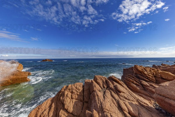 Coastal landscape with red rocks and surf in blue sky and sunshine, Spiaggia di Cala E'Luas, Ogliastra, Sardinia, Italy