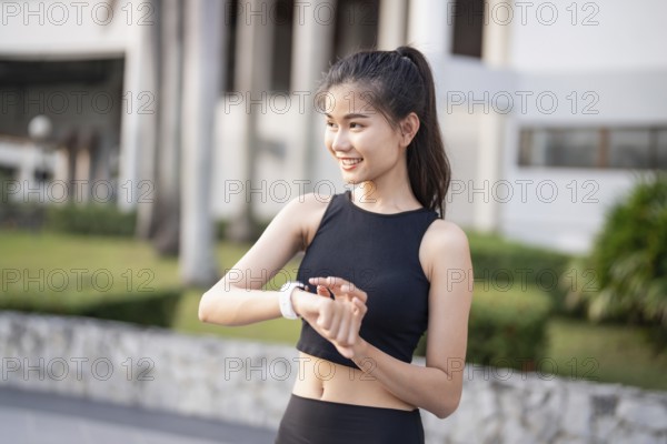 Sporty asian woman checking pulse in smart watch in sportswear workout with health app on smart watch After Exercise wellness health sportswoman