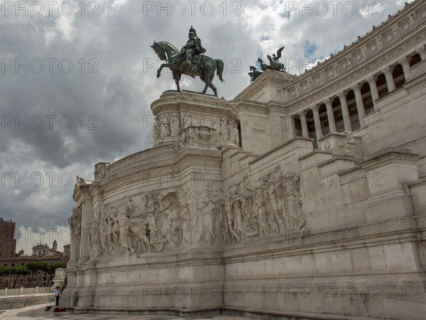Large monument with equestrian statue and detailed sculptures in the background of clouds, Rome, Italy