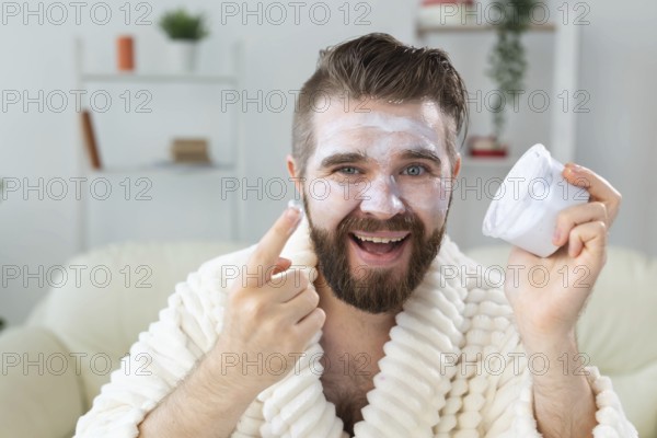 Bearded guy applying anti-wrinkle cream on his face. Skin care and spa for man concept