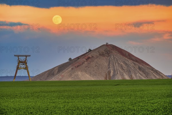 A view of an overburden heap in saxony-anhalt with a winding tower at moonrise