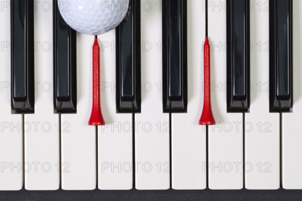 Virtuosic game - Piano keyboard and different golf balls and wooden tees
