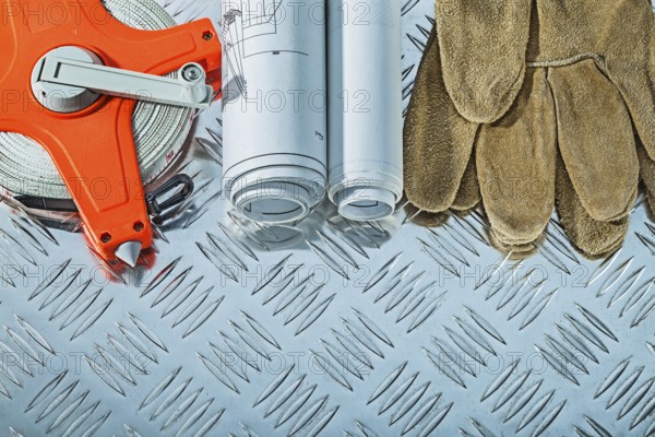 Blueprints safety gloves measuring tape on fluted metal sheet
