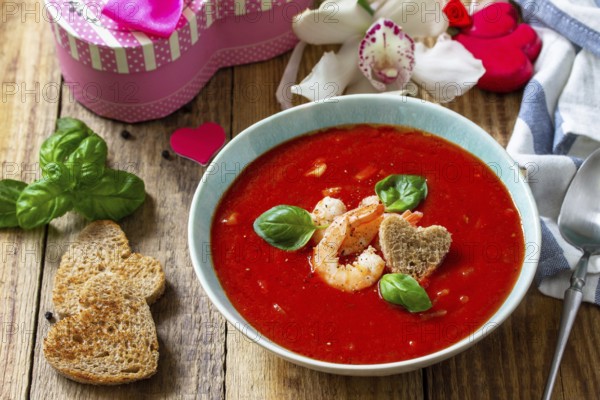 Homemade Valentine soup, festive food. Tomato soup puree gazpacho with tomatoes served seafood on a rustic wooden table