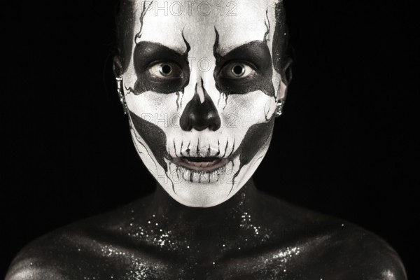 Isolated on black, closeup picture, beautiful young blonde caucasian woman with scull body art, grey eyes, penetrating look