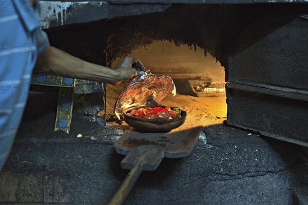 A community oven in the town of Tanger, which is used by a local and who is preparing some meal